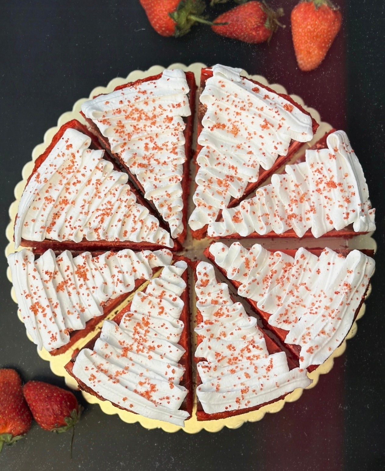 Dilimlənmiş red velvet tort, üstü krem və çiyələklə